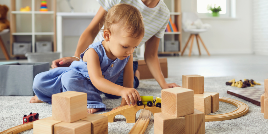 Filipino nanny playing trains with toddler