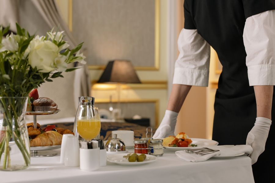 Professional butlers serving delicious breakfast setup