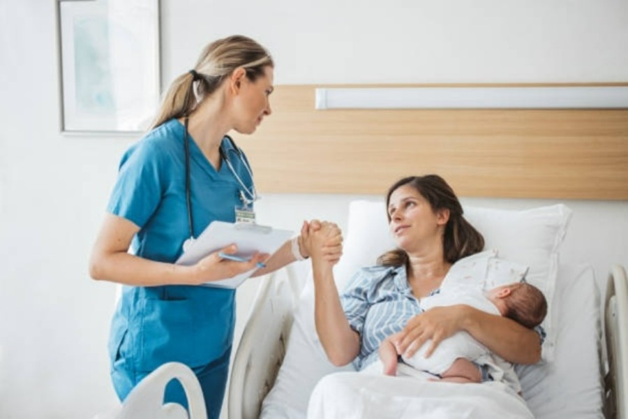 young mother and newborn assisted by maternity nurse